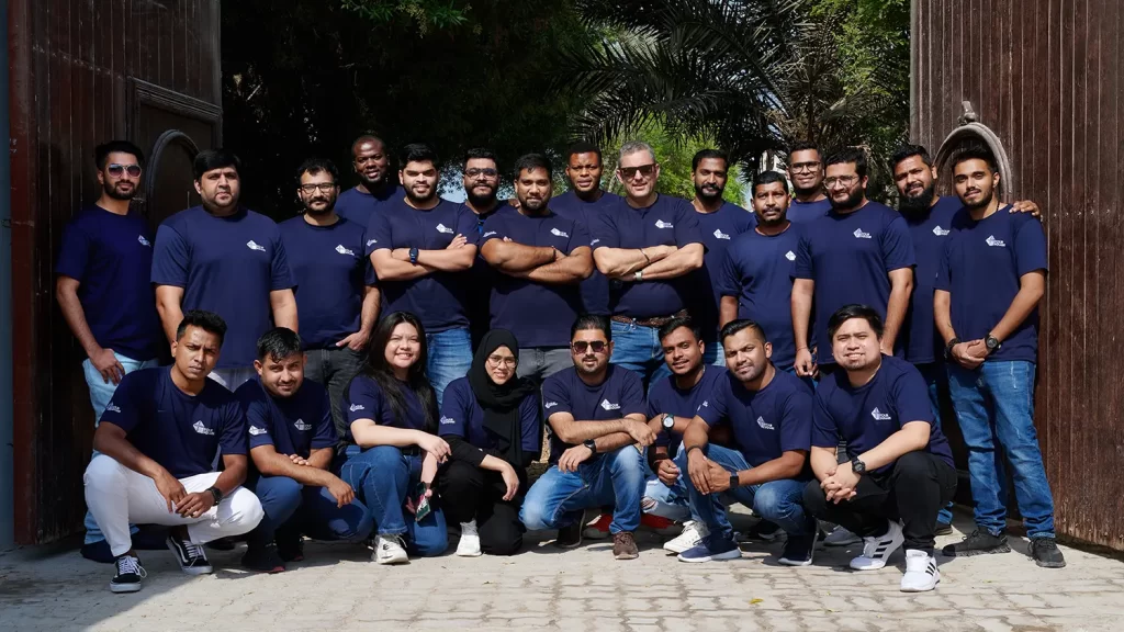 Foursquare team members in matching blue tshirts posing for a group photo outside.