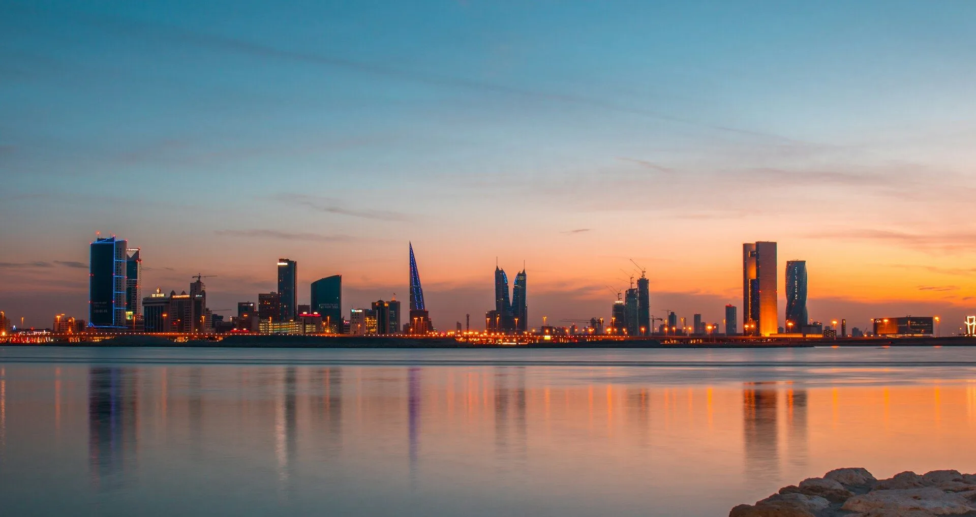 Manama, Bahrain city skyline at dusk as viewed from across the water sparkling with lights.